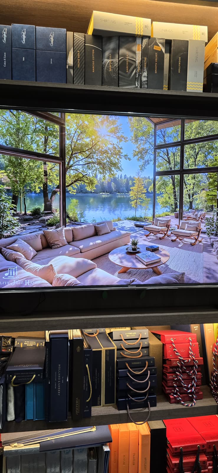 luxury store shelf display with a TV showing a modern lakeside house between gift boxes