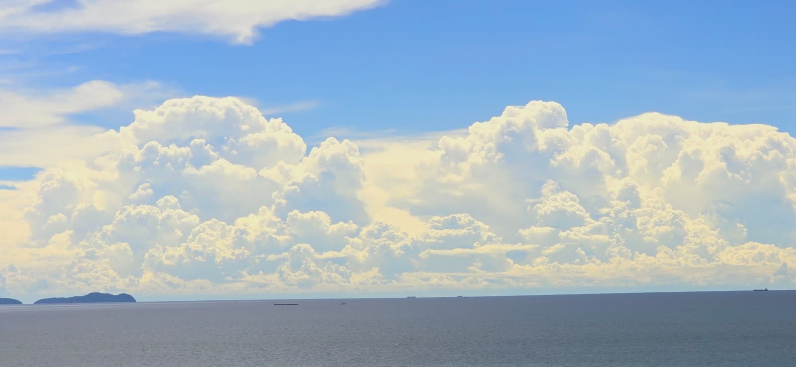 wide view of the ocean horizon with large cumulus clouds