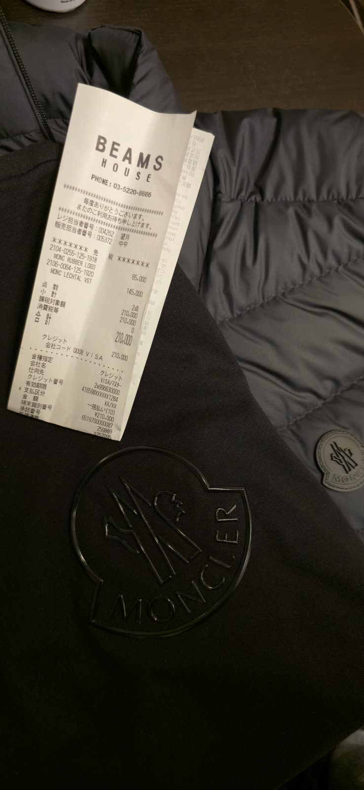 Beams House shopping receipt resting on a black Moncler jacket